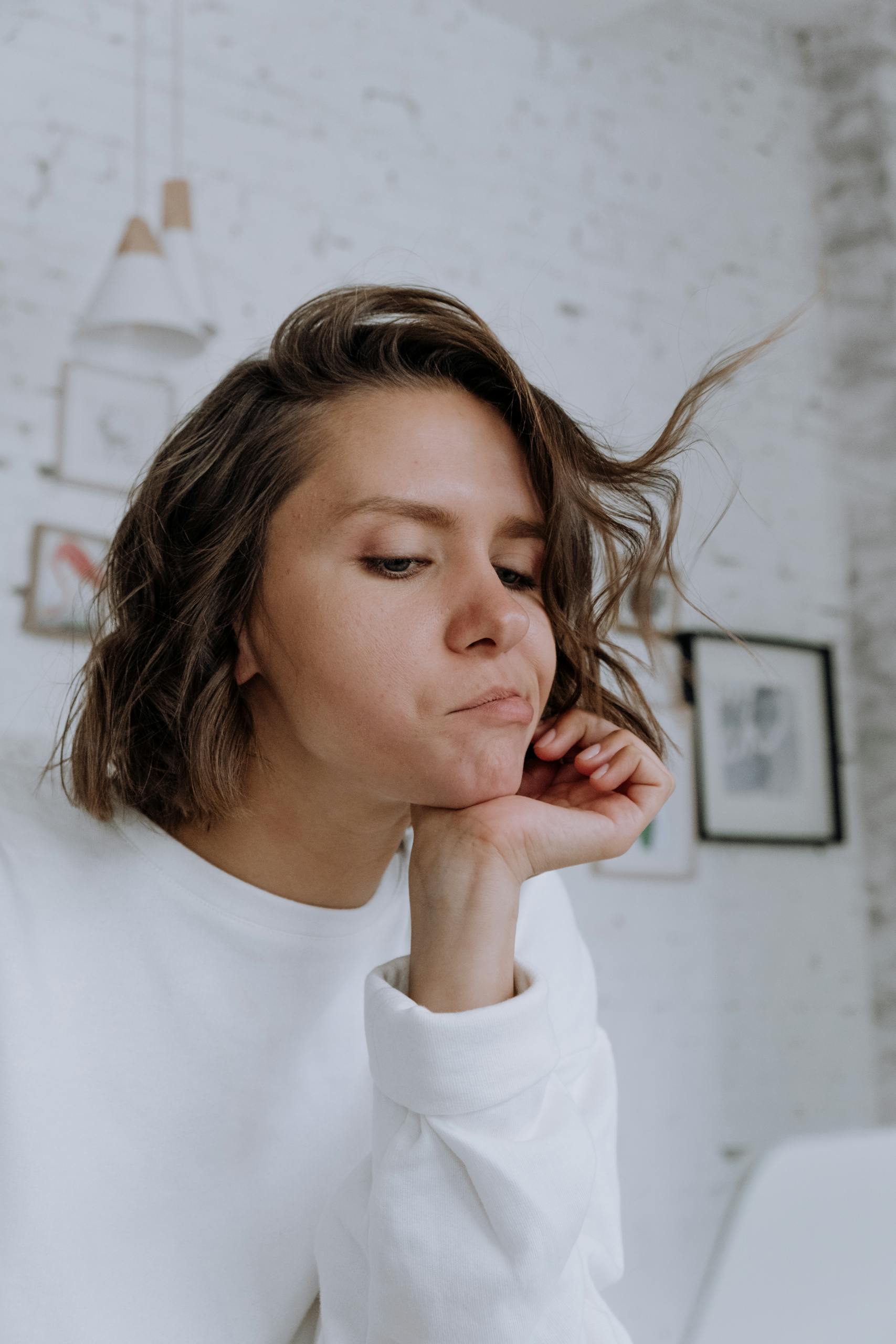 Young woman with bob haircut in a minimalist Scandinavian room, looking reflective.